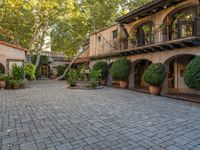 the courtyard and entrance to an apartment complex, with patios, bushes, and trees