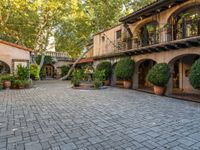 the courtyard and entrance to an apartment complex, with patios, bushes, and trees