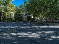 a brick road with trees and a parking lot in front of a building with green grass on both sides