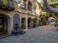 several trees are in pots on the brick patio under an archways with plants and stone pillars