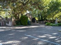 a driveway in the middle of a courtyard with trees and landscaping surrounding it and an archway