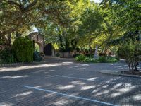 a driveway in the middle of a courtyard with trees and landscaping surrounding it and an archway