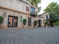 an old stone building is next to an entrance and patio with potted plants and bushes