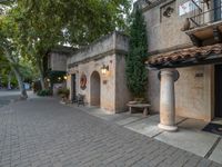 a stone brick sidewalk and an archway with columns, and a door and window in an old - fashioned building