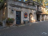 an old style building with an entrance on the side of the street and some potted plants