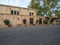 there is a courtyard area with brick walkways and plants growing on the walls and windows