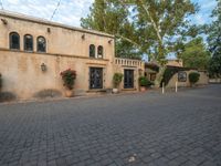 there is a courtyard area with brick walkways and plants growing on the walls and windows