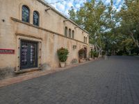 there is a courtyard area with brick walkways and plants growing on the walls and windows