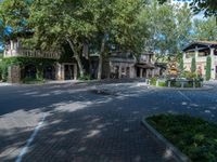 a beautiful courtyard area with some trees, houses, and fountain in it at a park