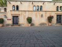 a building with many planters in front of it that is standing on top of a brick floor