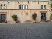 a building with many planters in front of it that is standing on top of a brick floor