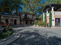 a very nice building with stone floors on a patio and a tree in front of it