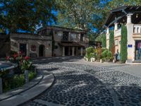 a very nice building with stone floors on a patio and a tree in front of it