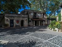 a very nice building with stone floors on a patio and a tree in front of it