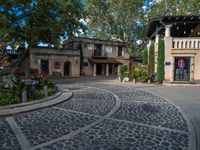 a very nice building with stone floors on a patio and a tree in front of it