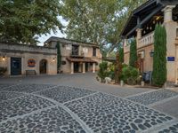 a very nice building with stone floors on a patio and a tree in front of it