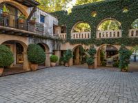 the courtyard with several potted plants and a wall full of green plants and arched arches