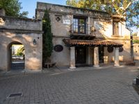 the entrance of this house is surrounded by greenery and trees and has a stone walkway