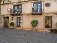 an old european building with black windows, iron guard railings and potted planters