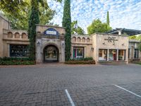 a courtyard area with a parking garage and shop fronts on the other side of the walkway