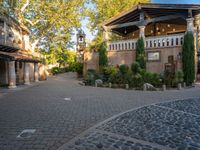 the outside area is made up of two different buildings and brick walkways and trees