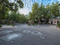 a circular driveway with parking spots and lots of trees around it and a cloudy sky