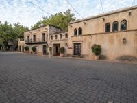 an image of the back of a building with pots in it and red flowers in the courtyard