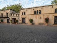 an image of the back of a building with pots in it and red flowers in the courtyard