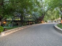 a brick paved path with trees on both sides of it and buildings on both sides