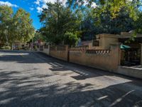 a view from the street of trees on the road near a sidewalk with a small gate