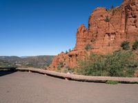 a person riding on a bike near some red rock formations and trees and a lake