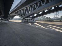 a semi truck is under a large bridge in the sun while some other vehicles are waiting under