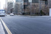 an empty city street filled with lots of traffic on the side of it and people waiting on a bench