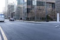 an empty city street filled with lots of traffic on the side of it and people waiting on a bench