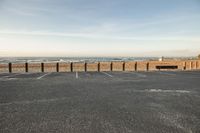 empty parking space with blue sky and sea on the horizon outside the concrete wall surrounding the parking lot