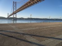 a person riding a bike on the side of a road near the bridge over water