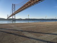 a person riding a bike on the side of a road near the bridge over water