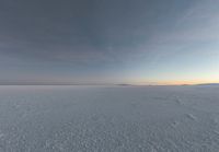 a man that is snow skiing on some ice field land in the winter time looking back to the camera