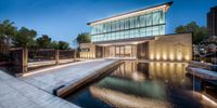 a large pool surrounded by a large glass wall and a fountain with lights on it