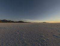 the snow covered ground is barren under a blue sky and there are many footprints in the snow