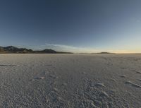 the snow covered ground is barren under a blue sky and there are many footprints in the snow