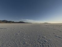 the snow covered ground is barren under a blue sky and there are many footprints in the snow