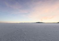 an image of a lake during the day that appears to be an empty field with snow on it