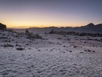 mountains and rocks in the distance as the sun rises over them on the horizon,