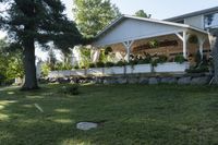 a large wooden structure in the grass with a stone wall to it and trees outside