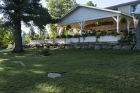 a large wooden structure in the grass with a stone wall to it and trees outside