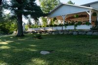 a large wooden structure in the grass with a stone wall to it and trees outside