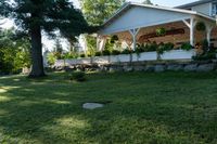 a large wooden structure in the grass with a stone wall to it and trees outside