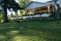 a large wooden structure in the grass with a stone wall to it and trees outside