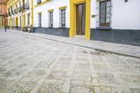 a yellow and black building on a city street with cobblestone road and a person sitting in a row